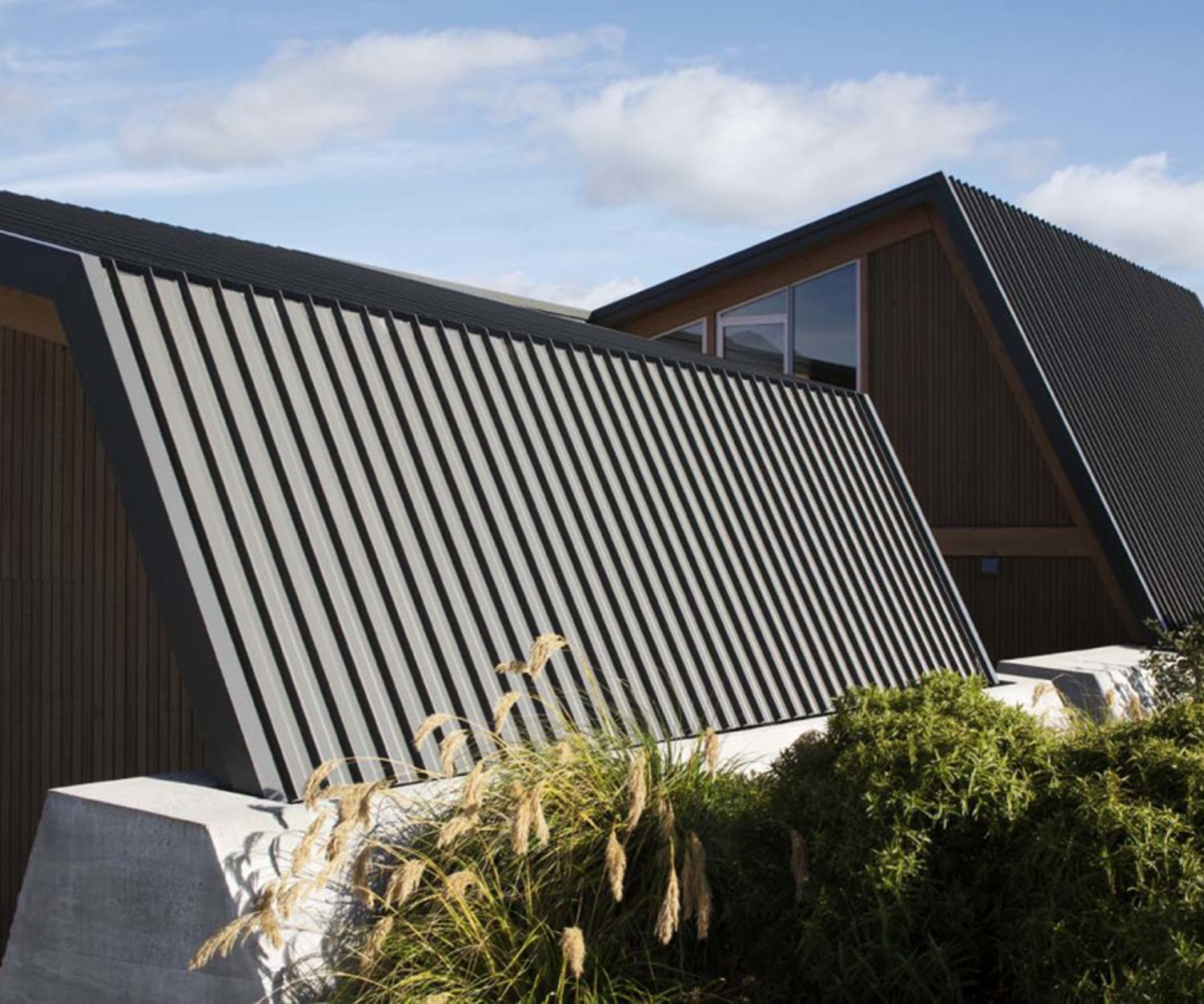 A low concrete wall anchors the home, inspired by schist bases of historic miners' huts in the region. 