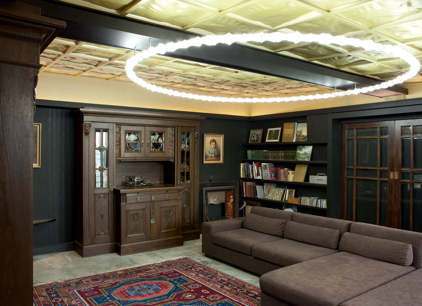 The living room ceiling panels look like traditional pressed ceilings but are made of vacuum-formed plastic; their shape is based on a 3D map of the region's terrain. The sideboard was built for Petra's great-grandparents' wedding around 1890. The portrait on the far wall is of Petra's father as a boy and was painted by her great-grandfather, Wilhelm Dohmann. The large circular light in the living room was designed by Ross in collaboration with his university colleague, Bernard Guy, and fabricated on a $1300 DIY 3D printer. Eighty separately printed 3D translucent diffusers were threaded over an aluminium tube that had an LED strip wound around it. Photograph by Simon Devitt.