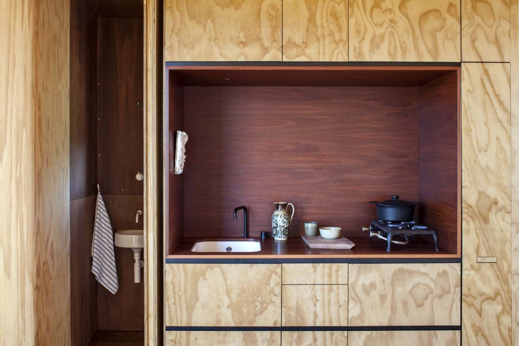 The other cabin is lined in plain builder's ply with a kitchen inset of oiled jarrah. The door to the small bathroom opens at left. Photograph by Darryl Ward. 