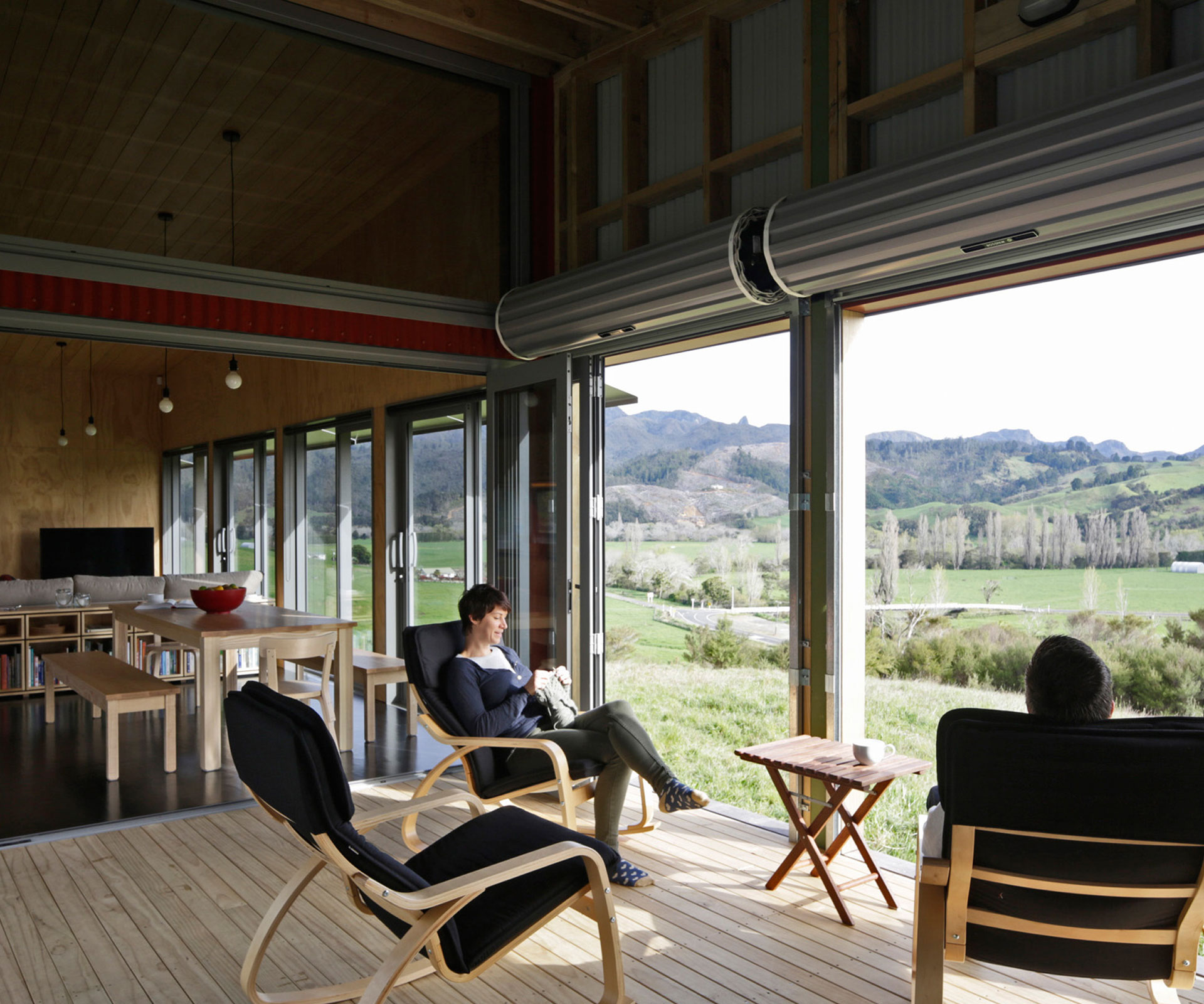 The central area of the shed-like holiday home by Richard Naish is a covered deck with roller doors that open to allow the breeze in. Photograph by Patrick Reynolds