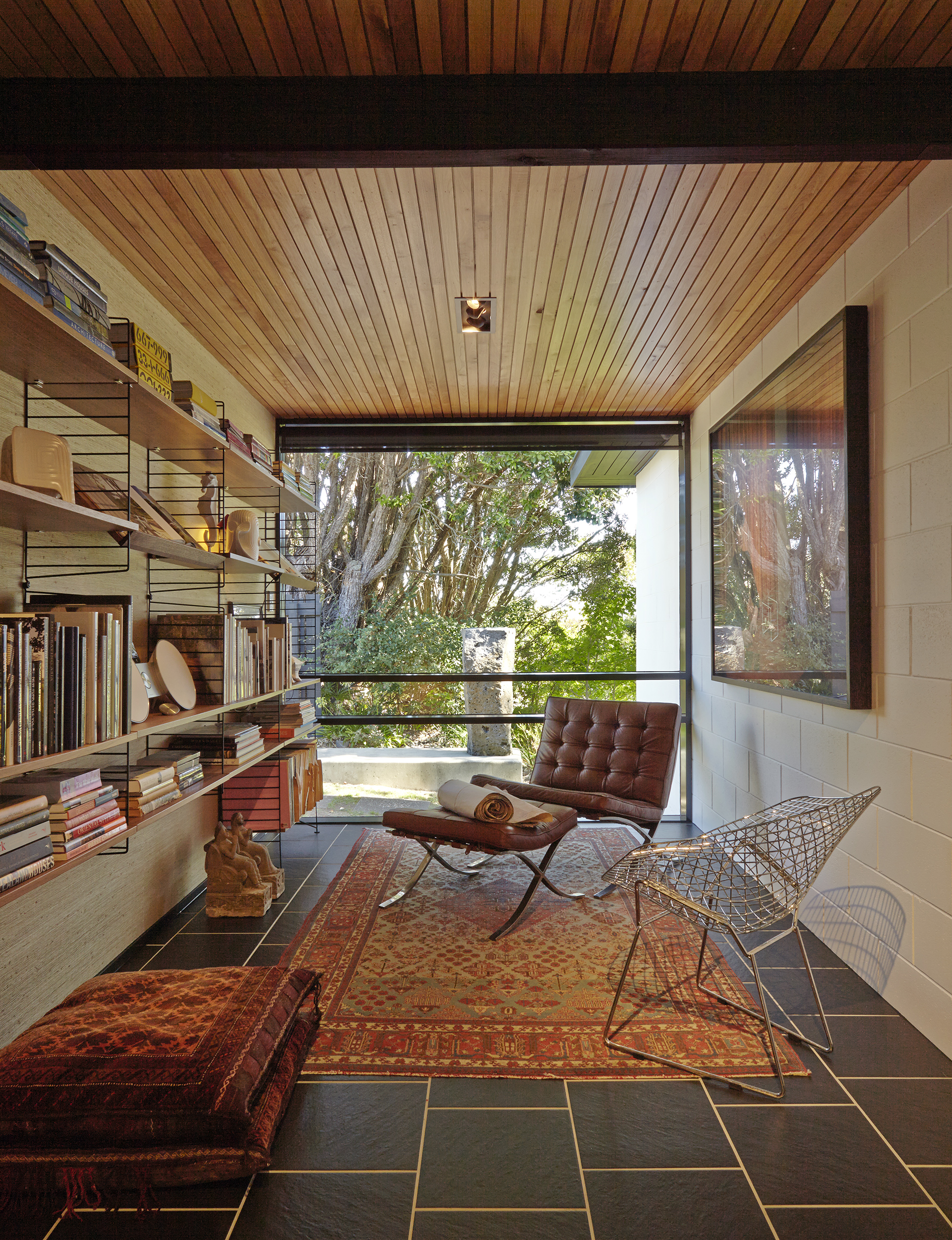 String shelving lines one wall of the library. On the facing wall is ‘Conversation of Momentum’ by Annika Koops. A ‘Barcelona’ chair by Ludwig Mies van der Rohe and Lilly Reich, and a ‘Diamond’ chair by Harry Bertoia for Knoll sit on an antique Kashmir rug. Outside is a sculpture by John Edgar. 