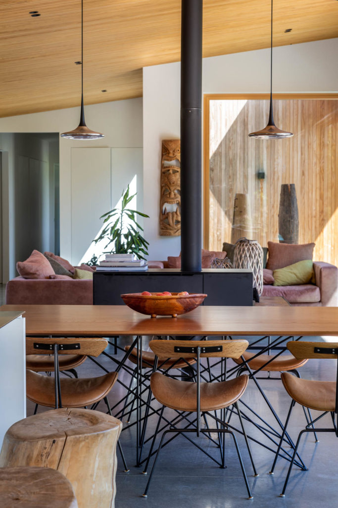 A view of the dining room with warm camel coloured furniture, a large wood burning stove and wood accents.